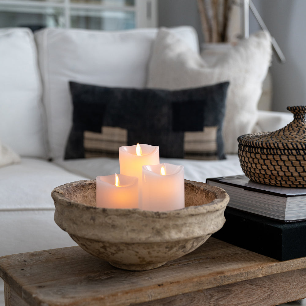 Flameless Candles inside of a paper mache bowl on a vintage coffee table