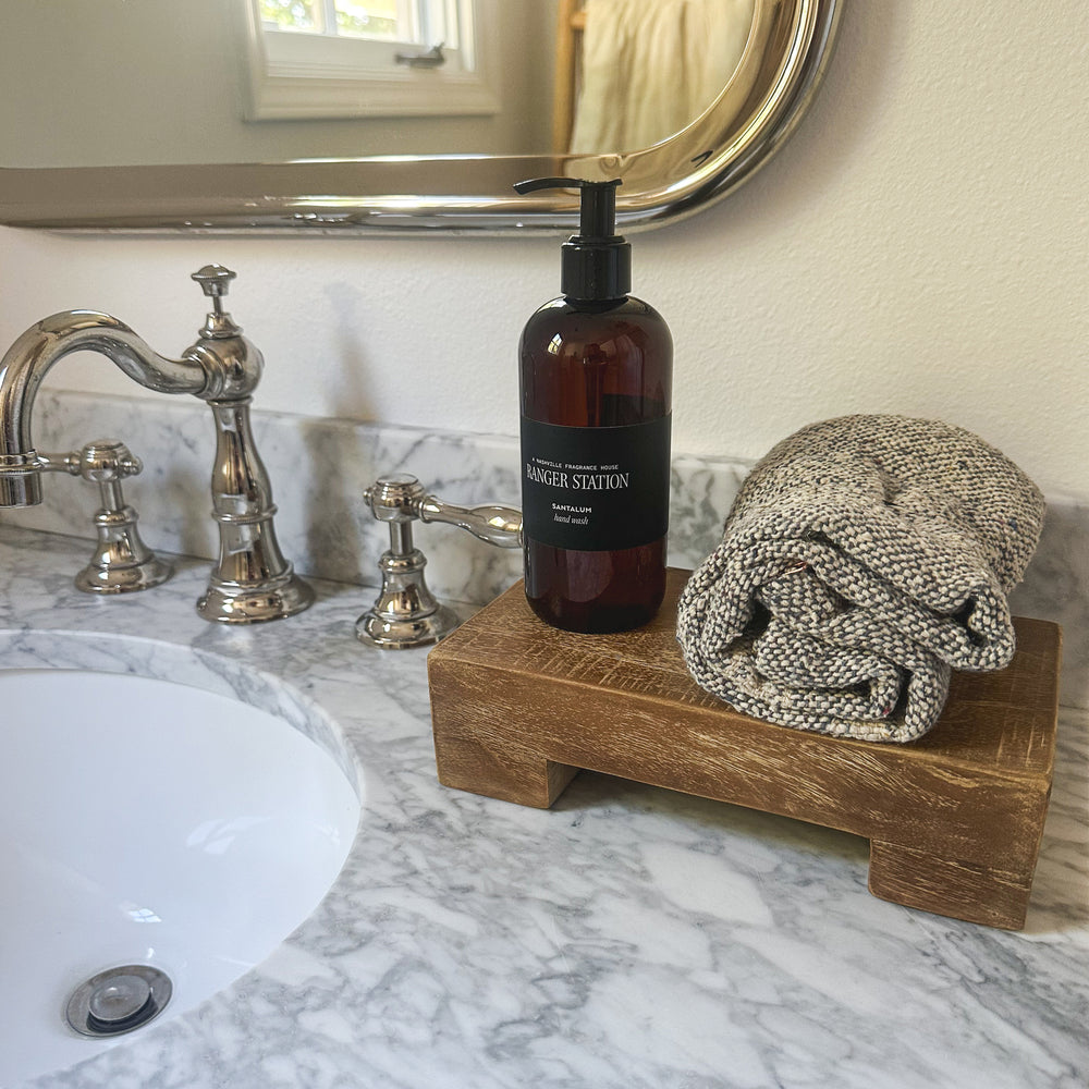 teak tray by a sink with soap and towel 