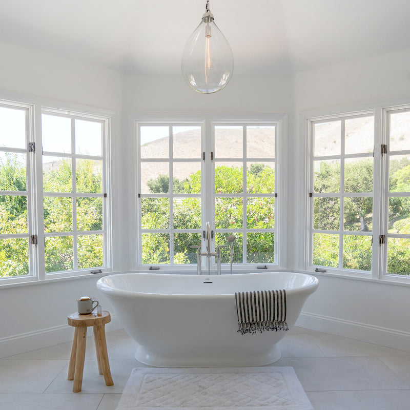 
                  
                    Teak stool by bath tub and windows
                  
                
